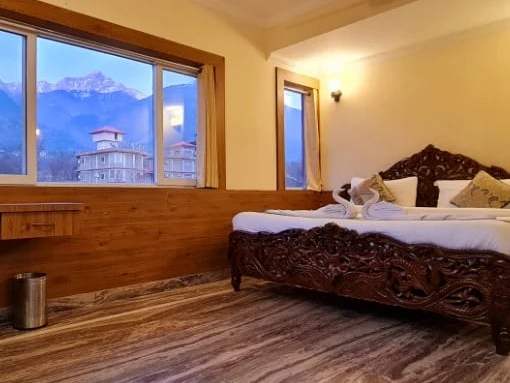 Suite Room: a carved wooden bed below a window with snow-capped mountains