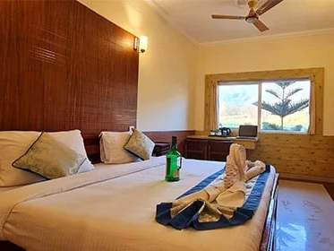 Superior room: a bed with blue throws and a window onto a tall pine and the mountains