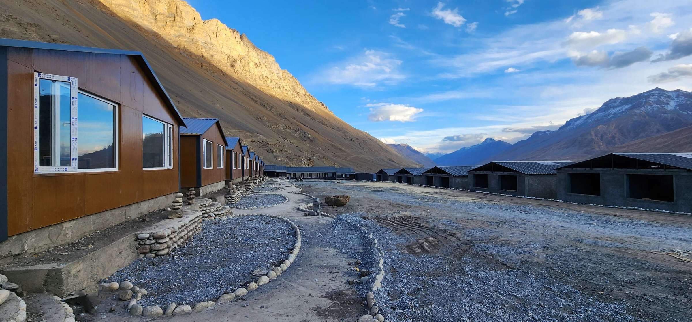 Spiti Villa’s cottages in summer, along a gravel path below bare mountains