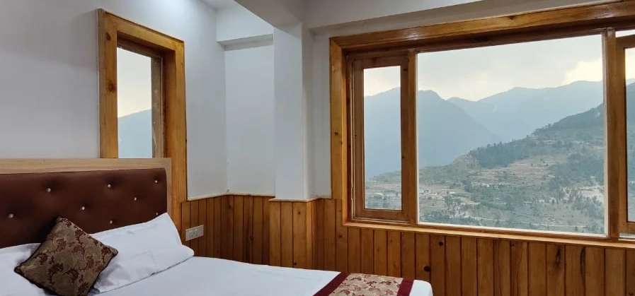 Premium room at Diwan: a wide window over a mountain valley, beside the bed