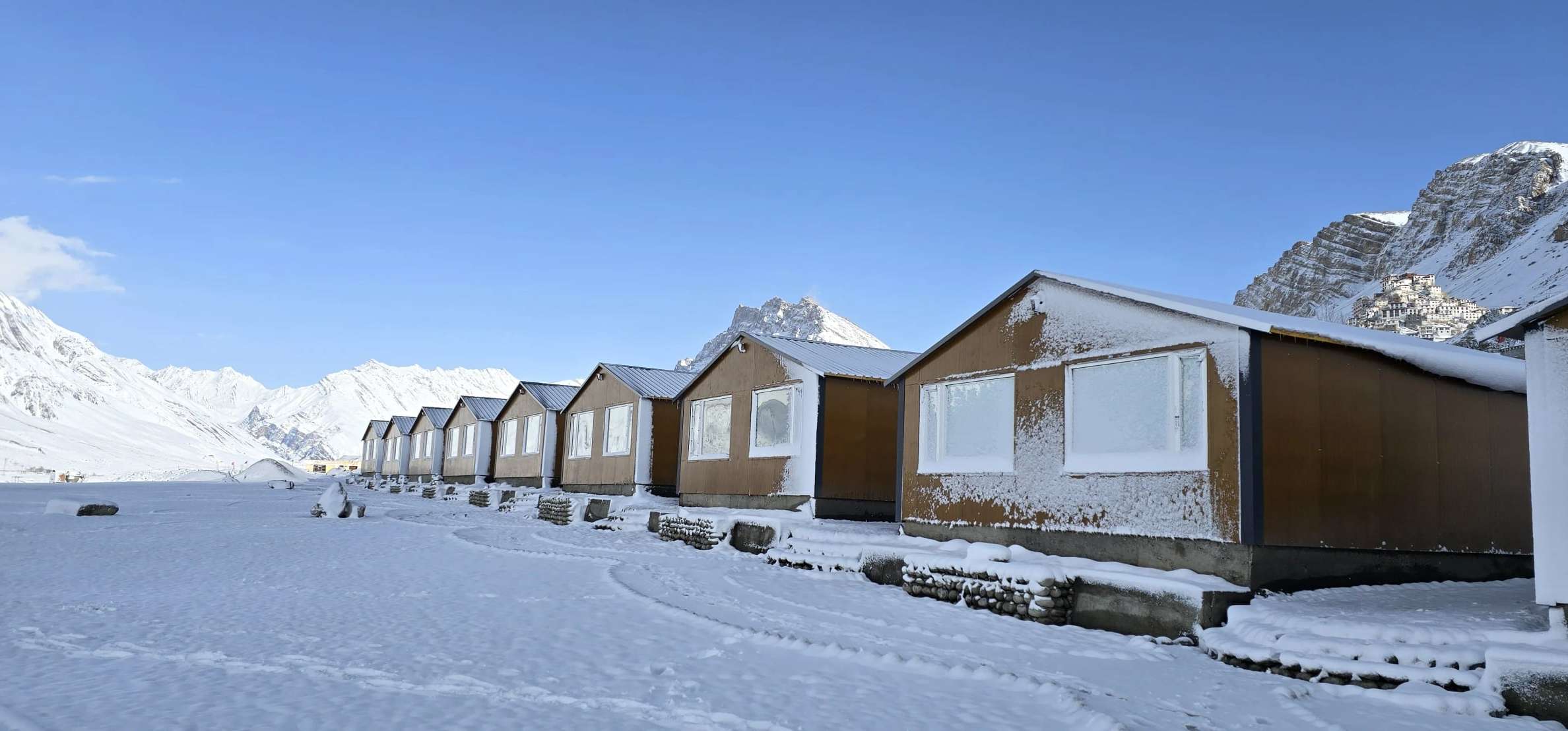The cottages under snow, with white peaks behind